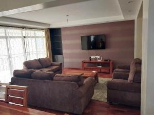 ein Wohnzimmer mit 2 Sofas und einem Flachbild-TV in der Unterkunft Sky view three bedroom in Nairobi