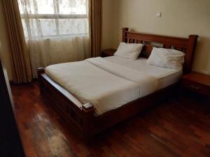 a bedroom with a large bed with white sheets and a window at Sky view three bedroom in Nairobi