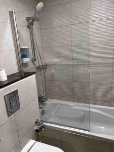 a bathroom with a shower and a tub and a toilet at Brand New Studio Near Dubai Airport in Dubai