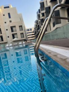 a swimming pool with a metal railing next to a building at Brand New Studio Near Dubai Airport in Dubai
