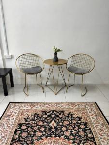 two chairs and a table in a room with a rug at Camelia Homestay in Seri Iskandar