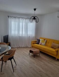 sala de estar con sofá amarillo y mesa en Apartments Ned, en Mandre