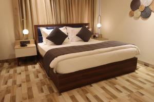 a bedroom with a large bed with pillows at Mastiff Hotel Dhanbad in Dhanbād