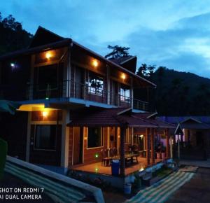 a house with a balcony and a patio at night at River Edge-Kudremukha in Kalasa