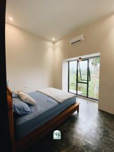 a bedroom with a bed and a large window at Kmanda House in Pangandaran