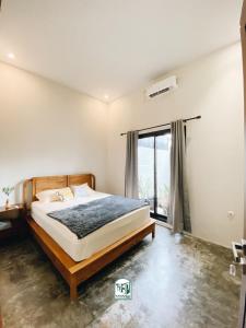 - une chambre avec un lit et une grande fenêtre dans l'établissement Kmanda House, à Pangandaran