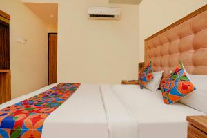 a bedroom with a large white bed with colorful pillows at FabExpress Emerald Inn in Mumbai
