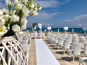 una cerimonia nuziale sulla spiaggia con sedie bianche e fiori di Hotel Lafayette a Giovinazzo