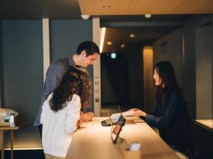 un homme et une femme debout autour d'une table avec un ordinateur portable dans l'établissement MIMARU TOKYO SHINJUKU WEST, à Tokyo