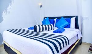 Ella Nimal Nest Inn في إيلا: سرير عليه وسائد زرقاء وبيضاء