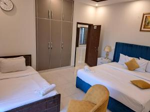 Un dormitorio con dos camas y una silla. en Cuzzy Inn Hotel, en Lahore 82 fotos más