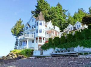 una gran casa blanca en una colina con árboles en Vancouver Castle Waterfront with hot tub beach downtown, en Chemainus