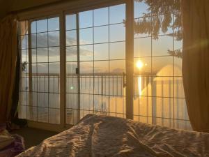 a bedroom with a large window with a view of the ocean at Vancouver Castle Waterfront with hot tub beach downtown in Chemainus