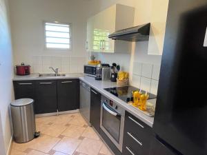 a kitchen with a sink and a stove top oven at La Croisette appartement vue mer à 1mn de la plage + parking in Filaos