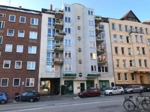 a tall building on a city street with parked cars at Stadtwohnung im Zentrum mit 24-7 Self Check-In, WLAN & Smart TV in Kiel