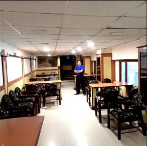 ジャンムーにあるHotel Surya Excellency By WB Innのテーブルと椅子の部屋に立つ男
