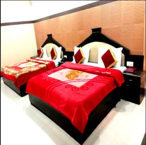 2 camas en un dormitorio con manta roja en Hotel Surya Excellency By WB Inn, en Jammu