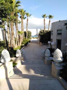 a pathway with benches and palm trees and a building at Hotel Lafayette in Giovinazzo