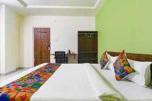 a bedroom with a large white bed with colorful pillows at FabHotel Golden Hitech in Hyderabad
