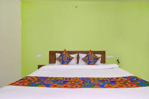 ein Schlafzimmer mit einem großen Bett mit bunter Bettwäsche und Kissen in der Unterkunft FabHotel Golden Hitech in Hyderabad