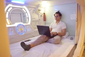 a man sitting on a bed with a laptop at Tab Hotel Legian Bali in Seminyak