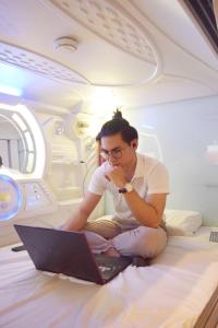 mężczyzna siedzący na podłodze z laptopem w obiekcie Tab Hotel Legian Bali w mieście Seminyak