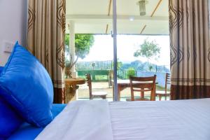 Bett mit blauen Kissen in einem Zimmer mit Terrasse in der Unterkunft Ella Nimal Nest Inn in Ella