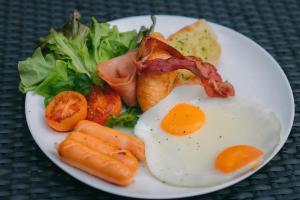 um prato de comida de pequeno-almoço com ovos, bacon e vegetais em The Zense Boutique Hotel em Phitsanulok