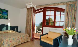 a bedroom with a bed and a chair and a window at La Locanda Azzurra in Sanremo
