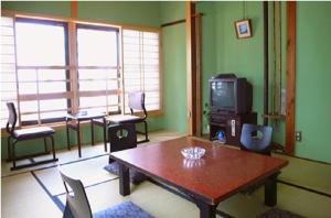 a living room with a table and chairs and a tv at Nisshokan in Ise