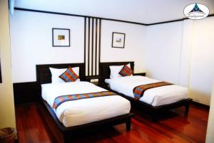 2 Betten in einem Zimmer mit weißer Bettwäsche in der Unterkunft Ping Phu Place in Chiang Mai