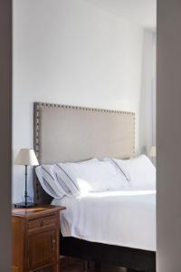 1 dormitorio con cama blanca y mesita de noche de madera en Hotel Tugasa Sierra y Cal, en Olvera
