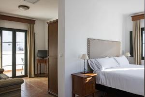 1 dormitorio con cama blanca y balcón en Hotel Tugasa Sierra y Cal, en Olvera