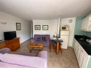 un soggiorno con divano viola e tavolo di Playa del Ingles Cosy Apartment a Maspalomas