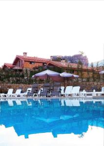 a swimming pool with white chairs and umbrellas at Villars in Mayrūbā