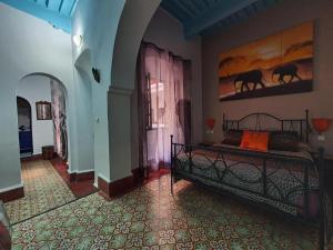 a bedroom with a bed and a painting on the wall at Riad Sidi Magdoul in Essaouira