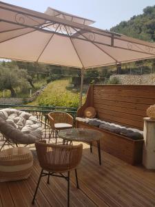 eine Terrasse mit Stühlen, Tischen und einem Sonnenschirm in der Unterkunft MARATHES STUDIOS in Agios Nikitas