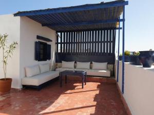 eine Pergola mit einem Sofa und einem Tisch auf einer Terrasse in der Unterkunft Riad Sidi Magdoul in Essaouira