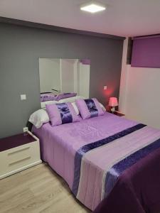 a bedroom with a large purple bed with a mirror at Precioso apartamento de 2 habitaciones. in Madrid