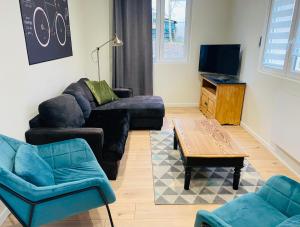 ein Wohnzimmer mit Sofas, einem Tisch und einem TV in der Unterkunft Le Biclou- 3 chambres in Bazincourt-sur-Saulx