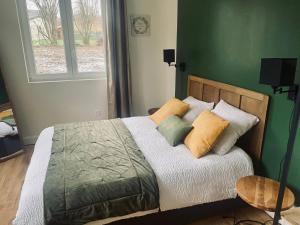 ein Schlafzimmer mit einem Bett mit Kissen und einer grünen Wand in der Unterkunft Le Biclou- 3 chambres in Bazincourt-sur-Saulx