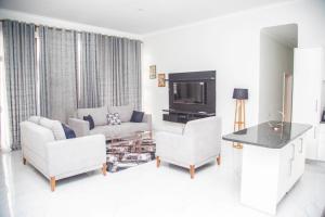 ein Wohnzimmer mit einem Sofa und einem TV in der Unterkunft Longhorn Executive Apartments in Lusaka