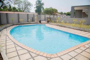 a swimming pool with blue water in a backyard at Longhorn Executive Apartments in Lusaka