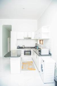 Biała kuchnia z białymi szafkami i zmywarką do naczyń w obiekcie Longhorn Executive Apartments w mieście Lusaka
