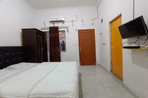 a bedroom with a bed and a flat screen tv at OYO 92176 Sandira Syariah in Dumai