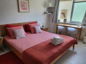 um quarto com uma cama com lençóis cor-de-rosa e uma mesa em The Rooms Upstairs & Downstairs em Amsterdã