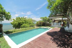 a swimming pool in front of a house with the ocean at Lombok Sunset Bay Resort in Sekotong