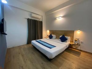 1 dormitorio con 1 cama blanca grande con almohadas azules en Divine Inn Couple Friendly Hotel near Sector 51 Metro Station, en Noida