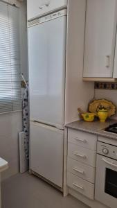 un frigorifero bianco in una cucina con armadietti bianchi di Hoyo 12 Islantilla a Huelva