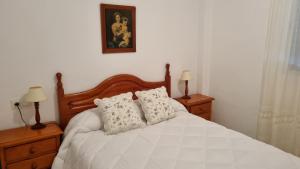 a bedroom with a white bed with two pillows at Hoyo 12 Islantilla in Huelva +22 photos